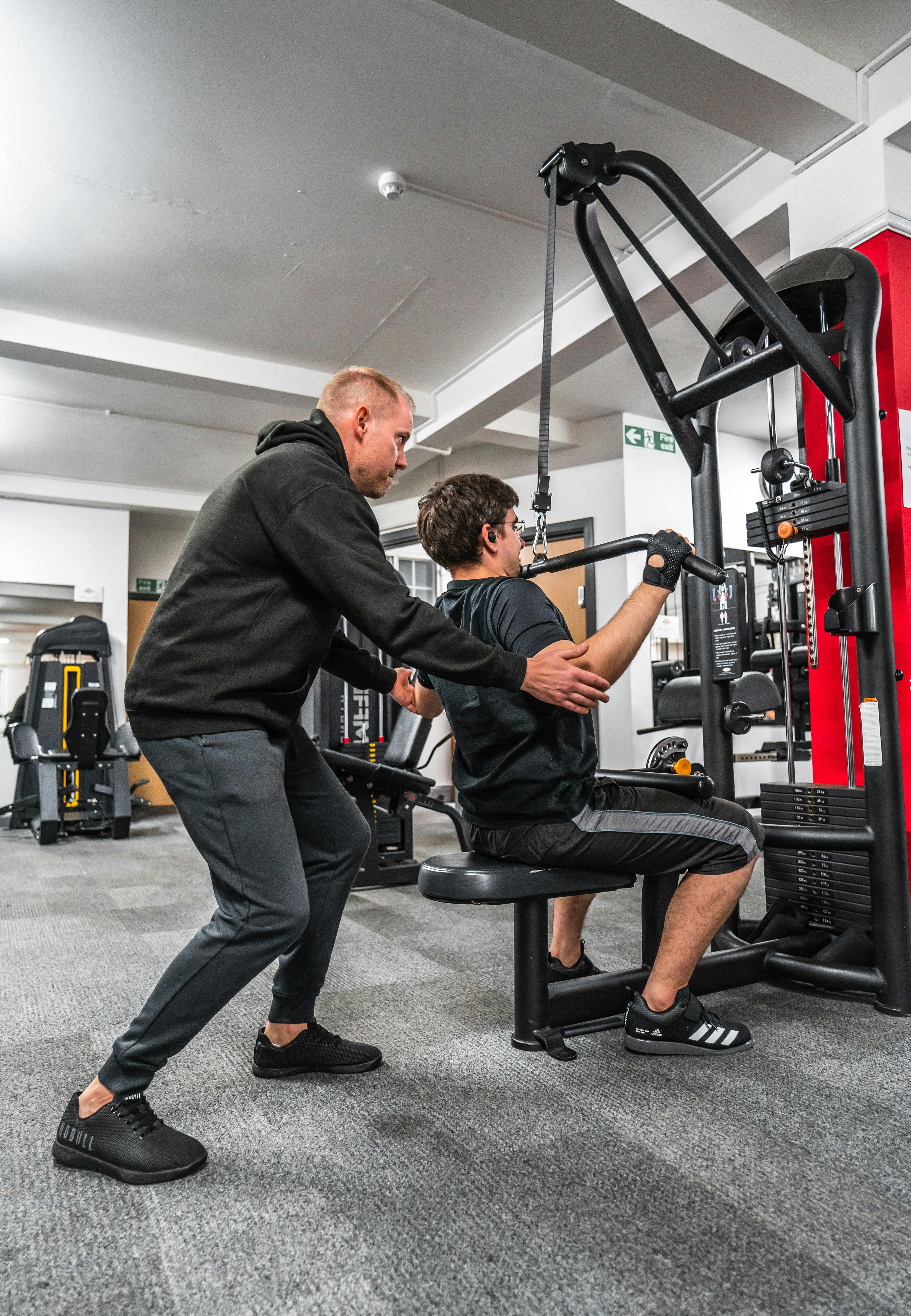 Coach supporting a client in a gym session